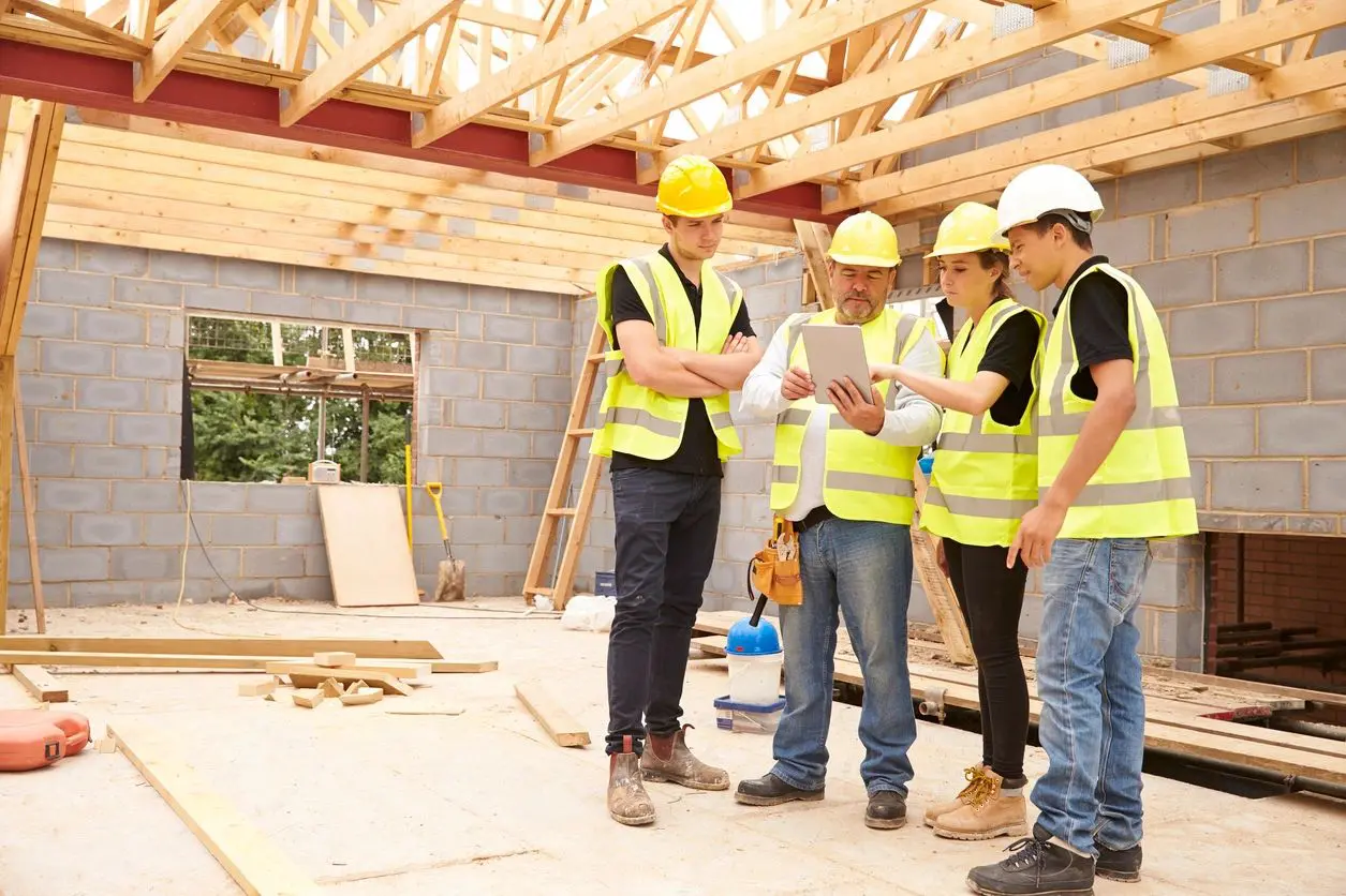 Builder on Site Looking at Digital Tablet With Apprentices